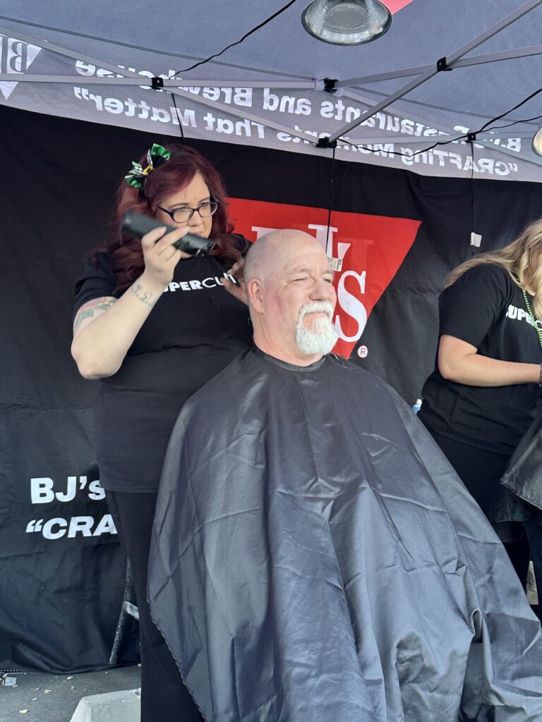 A gray-bearded man gets a trim under a tent from a stylist—just like Bell Brothers: trusted, upfront, and no surprise service.