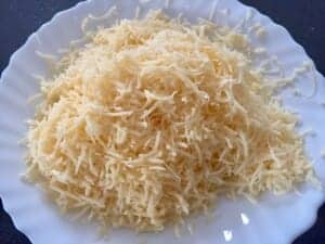 Drobno starty ser dodawany do sałatki z tuńczykiem w muszlach makaronowych