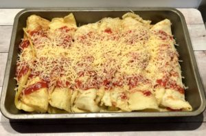 Naleśniki posypane serem przed pieczeniem.