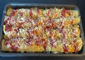 Naleśniki zapiekane z kurczakiem polane sosem pomidorowym i posypane serem.