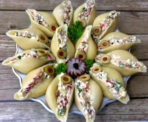 Gotowe muszle nadziewane łososiem i warzywami podane na talerzu