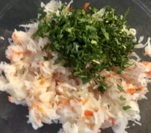 Surówka z kiszonej kapusty z marchewką i rukolą w trakcie przygotowania