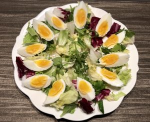 Jajka pokrojone na ćwiartki ułożone wokół sałaty
