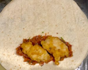 Układanie kurczaka na tortilli z warzywami