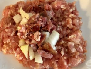 Rozpłaszczone mięso mielone z farszem przed zwijaniem roladek