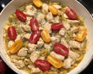 dodawanie pomidorków do kurczaka z makaronem w sosie serowym