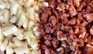 Cebula i kiełbasa pokrojone do farszu na roladki faszerowane z mięsa mielonego