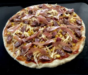 dodawanie sera i składników na pyszną pizza domowa przed pieczeniem