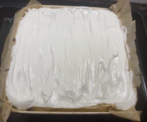 Nakładanie piany bezowej na sernik z kulkami makowymi