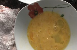 Mięso zanurzone w jajku jako etap przygotowania sznycli