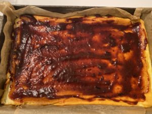 Smarowanie sernika powidłami śliwkowymi przed nałożeniem musu