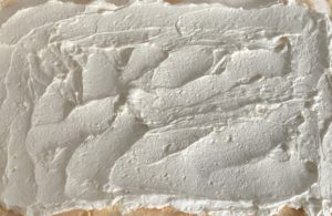 Nakładanie kremu na bezę w przepisie na roladę z wiśniami