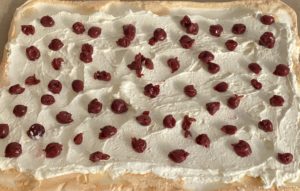 Układanie wiśni na kremie w roladzie bezowej