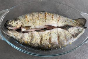 Surowy pstrąg ułożony w naczyniu żaroodpornym