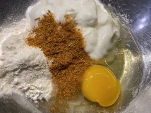 Składniki na kebabowe sznycle drobiowe w misce – jogurt, jajko, przyprawy i mąka.