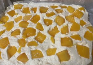 Pierwsza warstwa ciasta makowa Panienka z kremem i brzoskwiniami