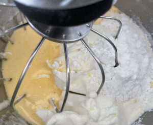 Dodawanie twarogu i śmietanki do masy serowej sernika snikers