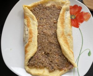 Zawijanie boków naleśnika przed rolowaniem krokieta