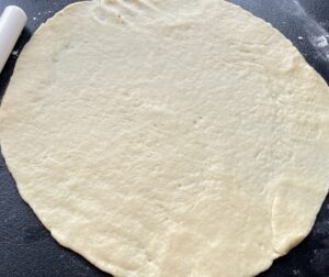 Rozwałkowane ciasto na kształt koła – przygotowanie rogalików z kajmakiem krok po kroku