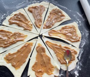 Nakładanie kajmaku na trójkąty ciasta na rogaliki – słodkie wnętrze