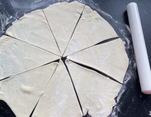 Podzielone na trójkąty ciasto na rogaliki z kajmakiem przed nadziewaniem
