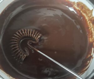 Rozpuszczona polewa czekoladowa gotowa do polania makowca w cieście.