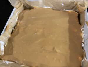 Nakładanie kajmaku na ciasto w przepisie na makowiec z karmelem