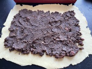 Masa makowa rozprowadzona na cieście do makowca w cieście kruchym.