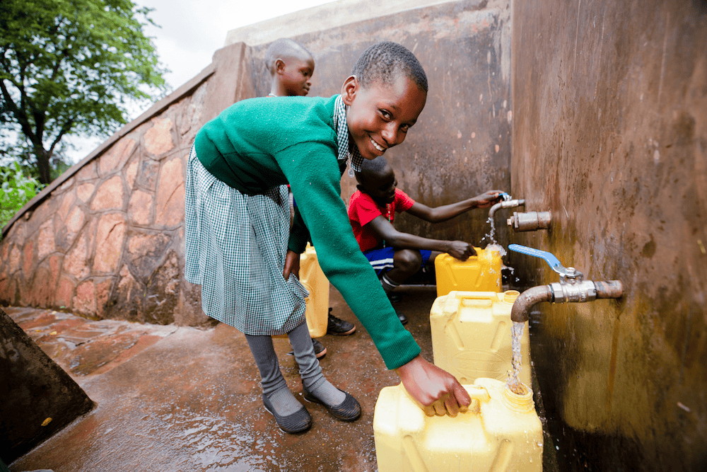 African students fill up their jerrycans at a well at their school