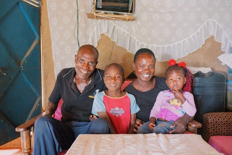 a family sits in their living room, all smiling at camera