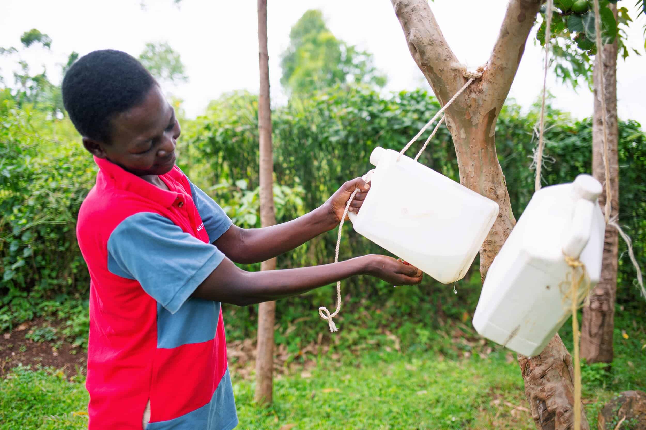 woman uses a tippy tap (a type of hand-washing station)