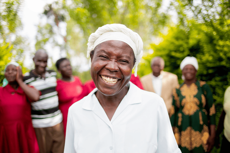 woman wearing a white bonnet smiling brightly at camera