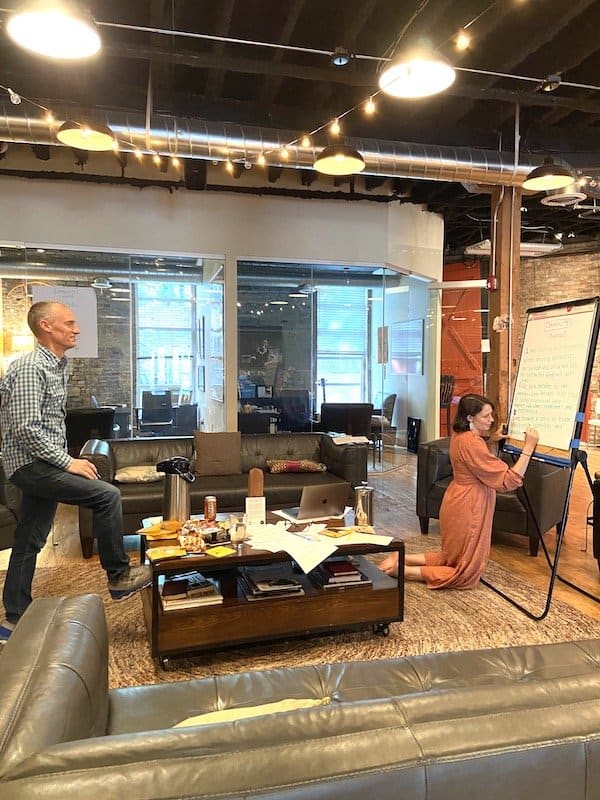 Man and woman writing on white board