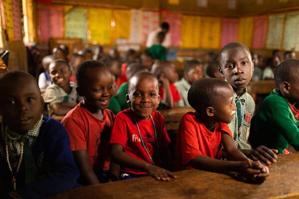 school children in africa laugh as they sit in a classroom together