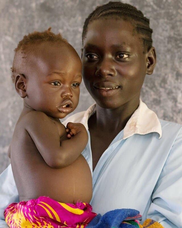 woman holding a baby stares off to the side