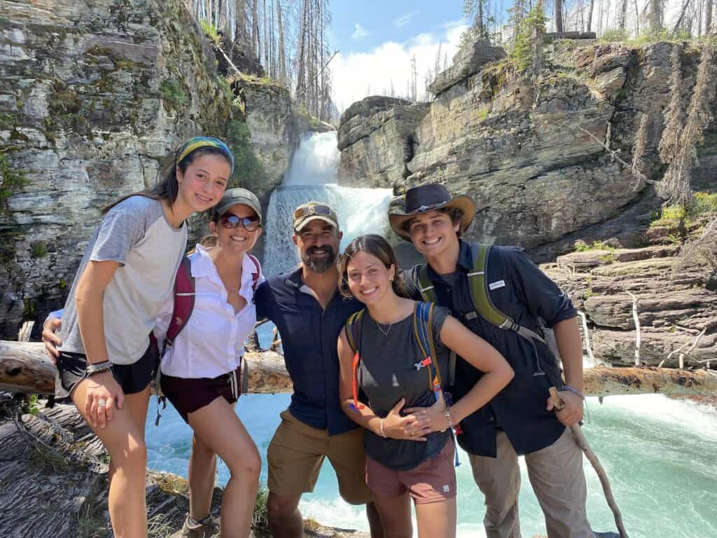 five family members posed in front of waterfall