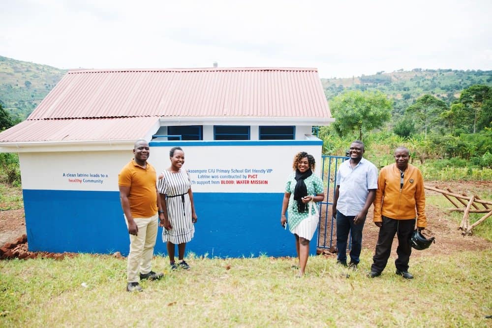 five people standing in front of girl friendly latrine