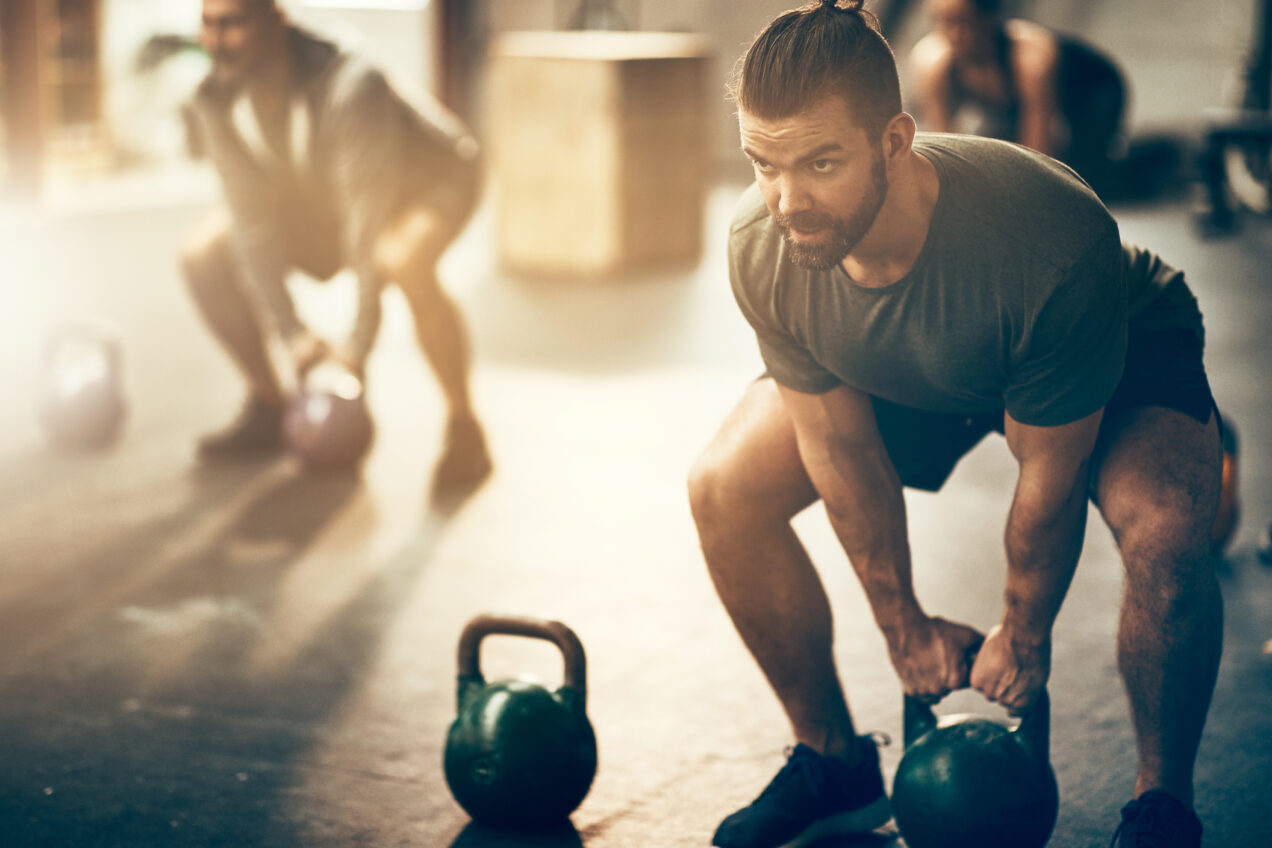 A man squats and grabs hold of a kettlebell