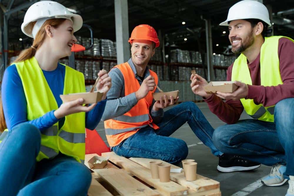 Group,Of,Smiling,Workers,Wearing,Hard,Hats,,Vests,,Holding,Lunch