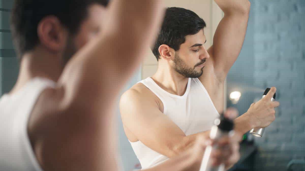 how does deodorant work man spraying deodorant