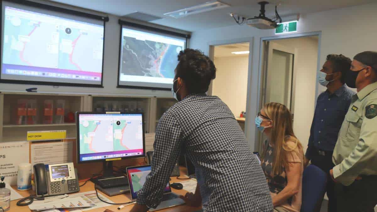 A group of people look at birds eye view computer modelling.