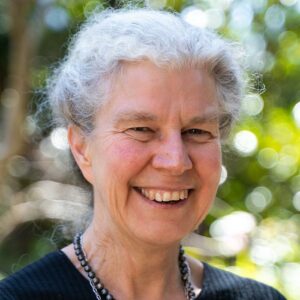 An older woman with grey hair smiles at the camera