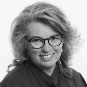 A black and white photograph of a woman smiling at the camera