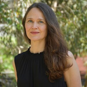 A woman with long brown hair smiles at the camera