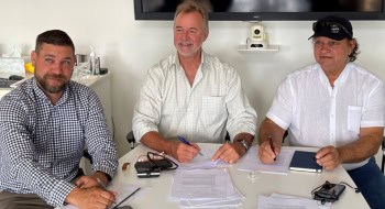 Three people sitting around table with documents