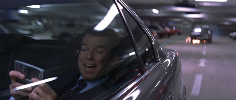 Scene from a bond movie showing james bond in a car using a mobile phone.