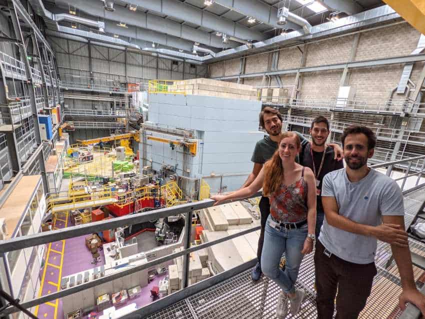 Four people stand on railing above lab