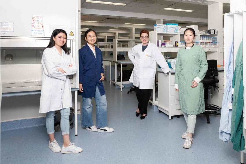 Renae ryan and colleagues wearing lab coats in a biology laboratory