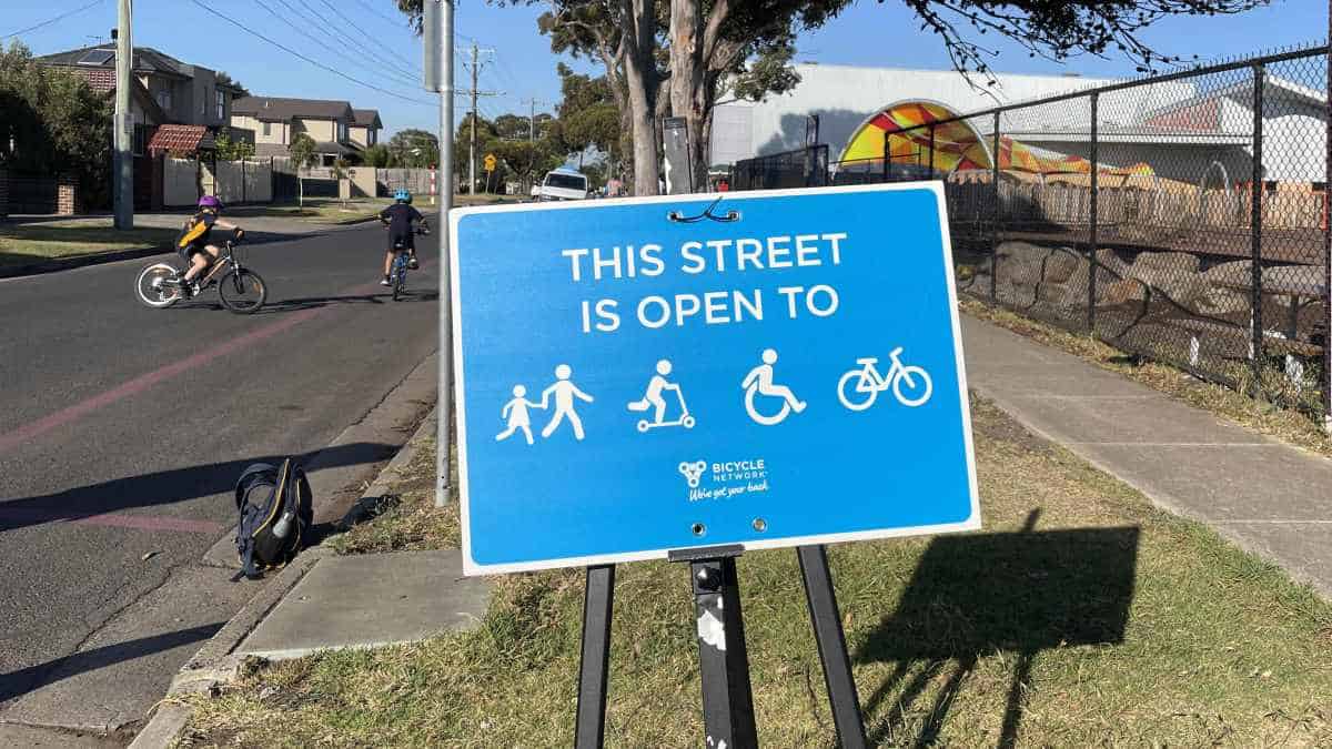 A blue sign that reads "this street is open to walking, scooter, wheelchair, bikes"