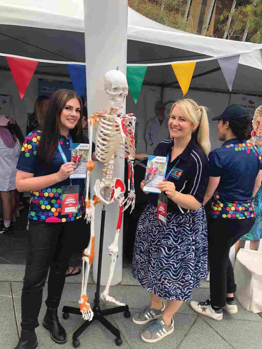 Two women pose with a skeleton.